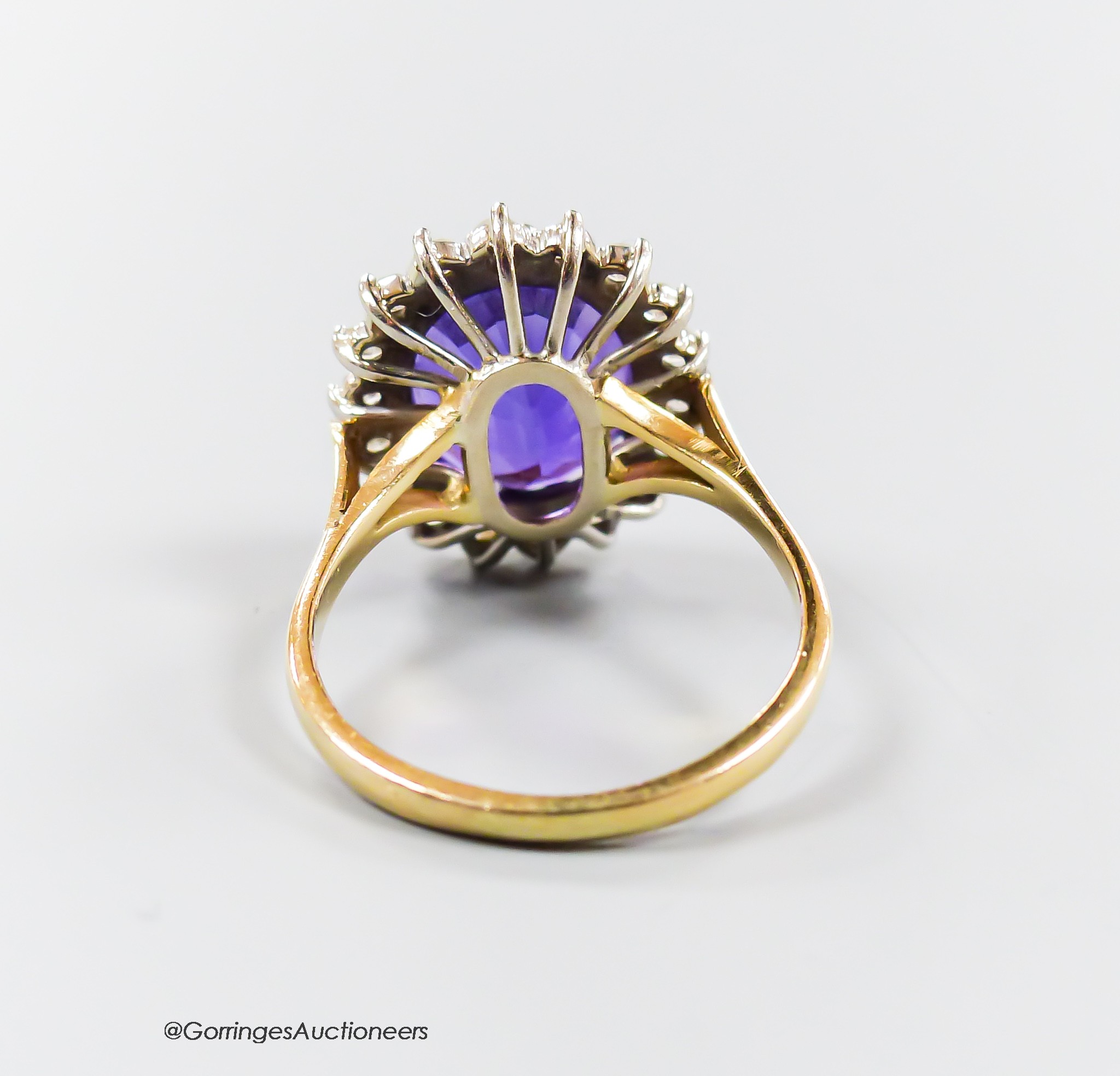 A modern yellow metal, amethyst and diamond set oval cluster ring, size O, gross 5.6 grams.